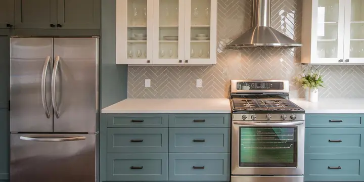 Kitchen with teal shaker cabinets, stainless appliances and a herringbone tile backsplash