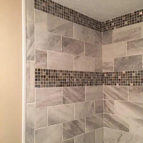 Tiled shower wall with a dark mosaic accent band