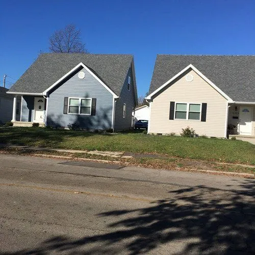 Two small homes with gray and cream siding on a residential street