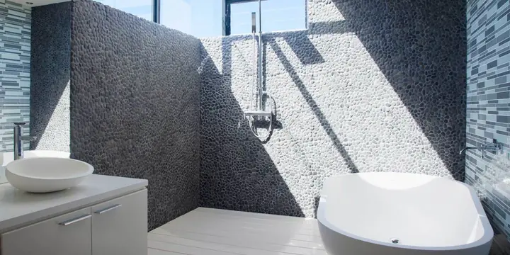 Spa-style bathroom with a pebble-tile shower wall and freestanding tub