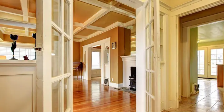 Interior French doors and a coffered ceiling above hardwood floors